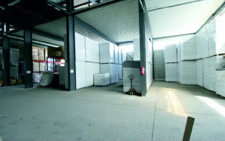 Innenansicht der Lagerhalle mit gestapelten Dämmstoffplatten und offenen Lagerflächen für Materialien.