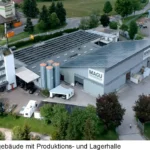Luftaufnahme des MAGU-Verwaltungsgebäudes mit angrenzender Produktions- und Lagerhalle in Hüfingen. Die Solaranlage auf dem Dach zeigt das nachhaltige Energiekonzept des Unternehmens.