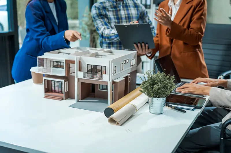 Planung eines energieeffizienten Bausatzhauses mit Modell am Tisch und Beratung im Team