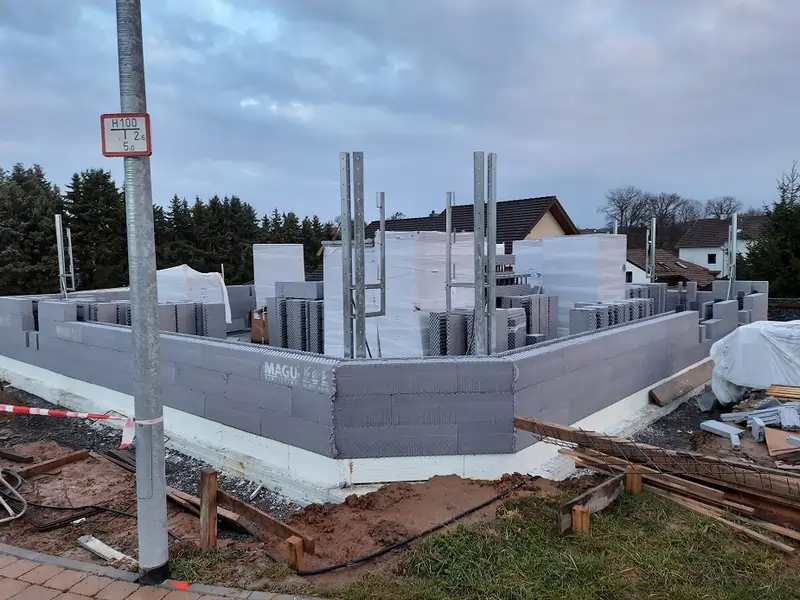 MAGU Baustelle in frühem Stadium mit montierten Richtstützen und gestapelten Schalungselementen, bereit für den weiteren Wandaufbau.